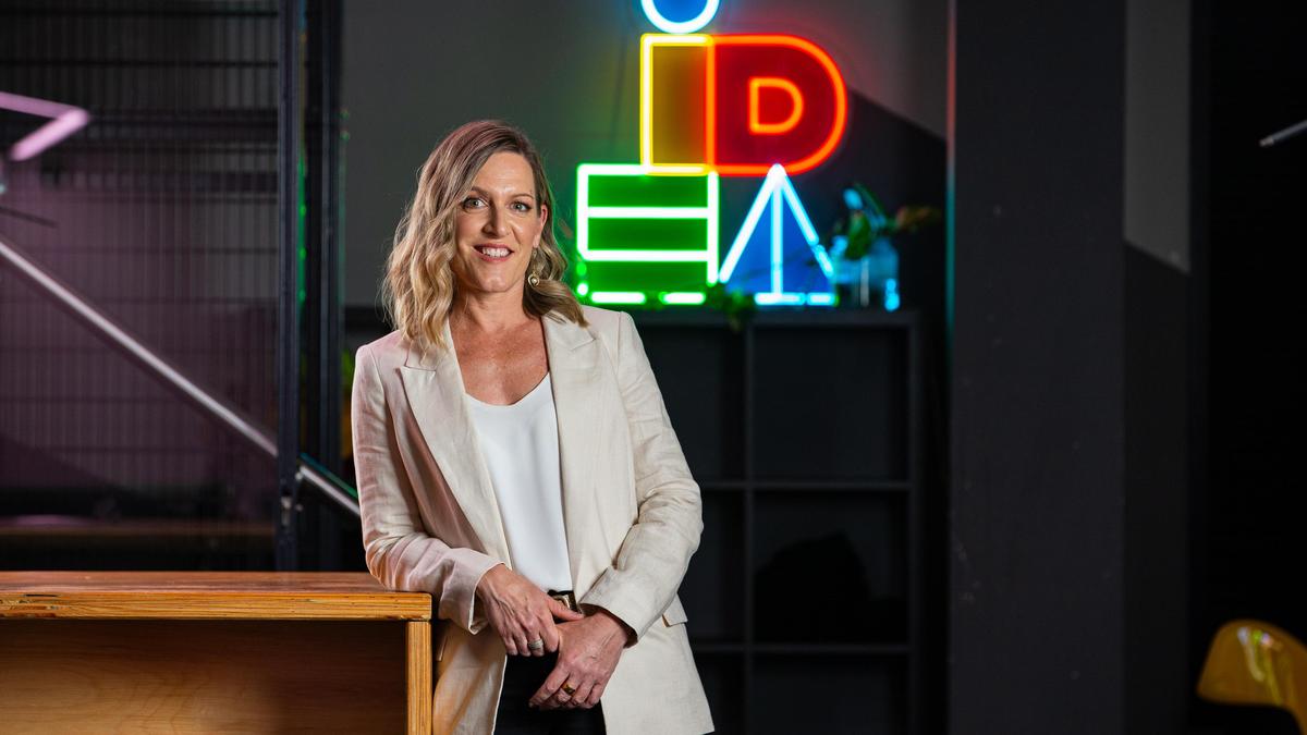 Idea Academy leader standing in front of the academy’s neon logo
